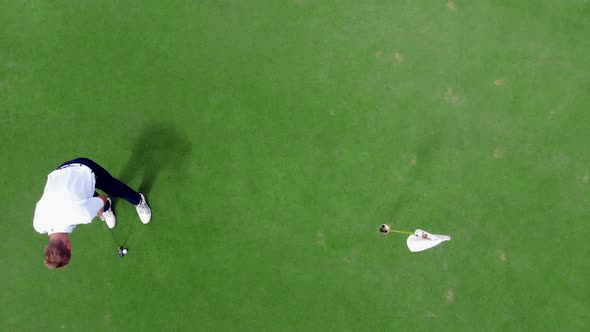 Person Plays Golf on a Green Course, Putting a Ball Into Hole alt