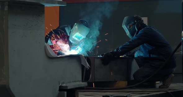 Two Men Wearing Welding Masks Are Working at the Factory Welding alt
