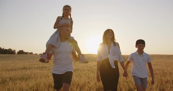 A Young Happy Family With Children Is Walking In The Field