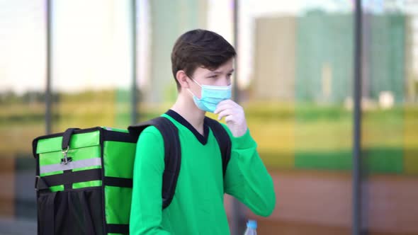 Young Courier Drinks Water From a Plastic Bottle. alt