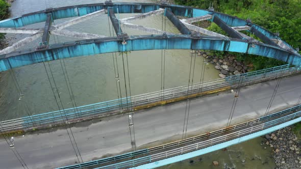 Aerial view, moving from the side towards a top view of a metal truss bridge alt