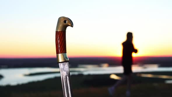 Swords Training  Young Woman Training on Nature While Sunset  Sword Handle on the Foreground alt