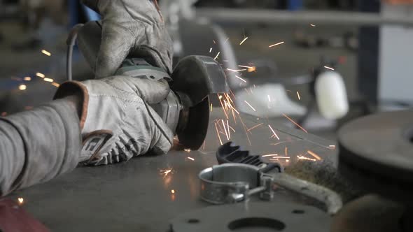 A Worker Works With A Grinder. Hands Of Workman Cutting Metal Detail With Grinder