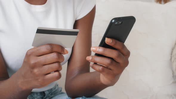 Closeup Young African American Female Shopper Holding Smartphone and Credit Card in Hands Using alt