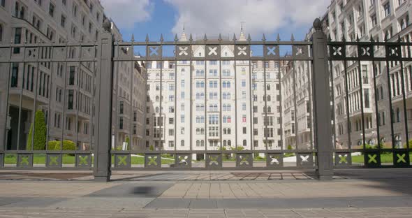 Black Dachshund Runs Past Steel Fence of School Building alt