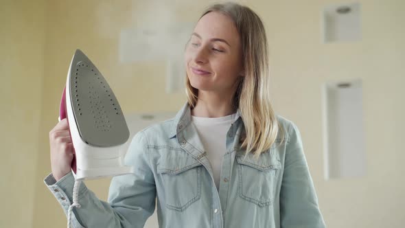 Woman Ironing Clothes at Home. Holds an Iron in His Hand alt