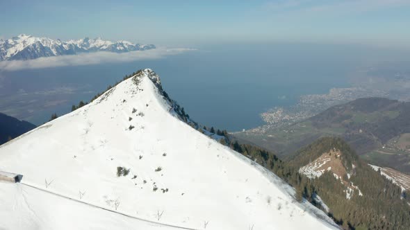 Aerial reveal of beautiful green valley in a snow covered mountainscape alt
