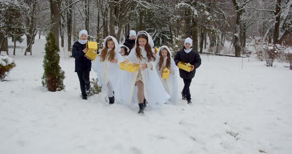 Children With New Year's Gifts Run Through The Woods. Play In The Snow