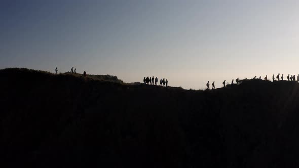 Hikers at the summit of Mout Batur volcano in Bali Indonesia walk along the crater ridge, Aerial orb alt