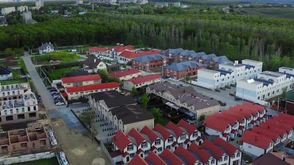 A Lot of Different Townhouses in the Forest with Bright Roofs  the Construction of New Housing alt