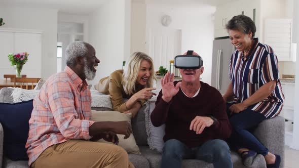 Two diverse senior couples sitting on a couch caucasian man is using vr googles alt