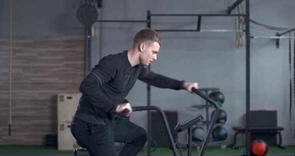 Young Man Trains on a Elliptical Bike Simulator Aerobic Exercise and Endurance Training alt