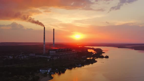 Factory chimneys with smoke. Beautiful sunset over river. View from the top. alt