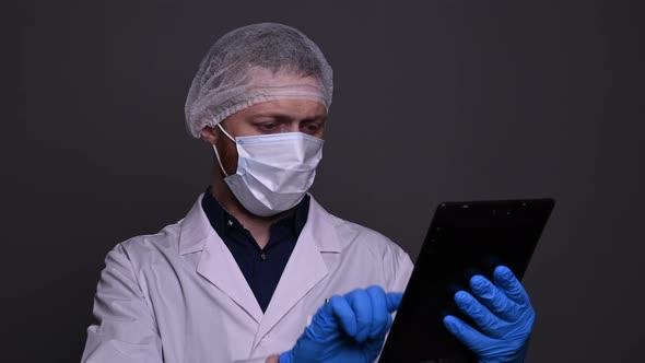 Caucasian male doctor swiping the tablet, puts the tablet away, looks at camera alt