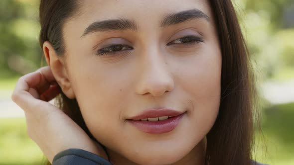 Attractive Young Lady Posing Touching Hair And Smiling Outdoors alt