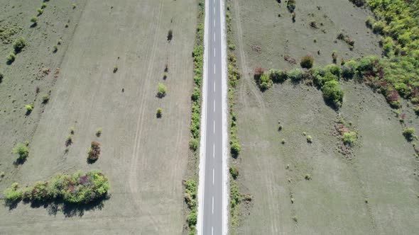 Top Aerial View of an Empty Asphalt Road on the Plateau Between Green Fields alt