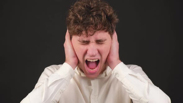 Young Stressed Man Covering Ears with Hands Screaming Shouting alt
