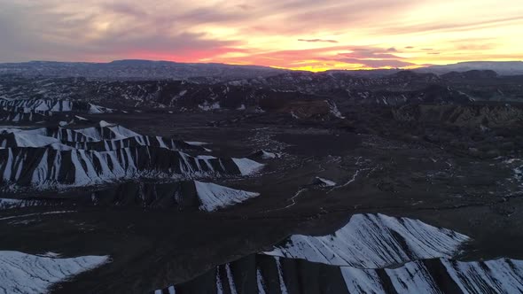 Flying along snow stripes on dunes in the desert during colorful sunset alt