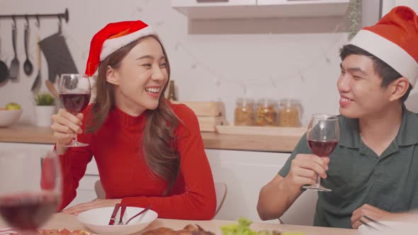 Asian happy family having christmas party, clinking wine glasses on table together at home. alt