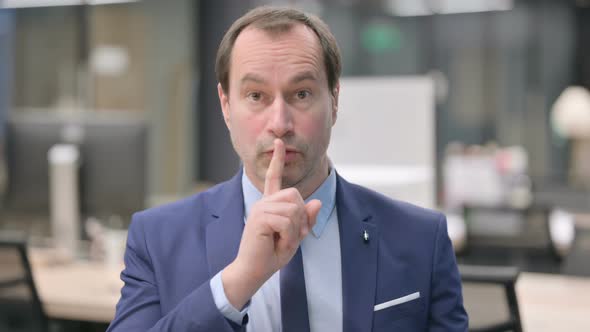 Portrait of Businessman Putting Finger on Lips Silence alt