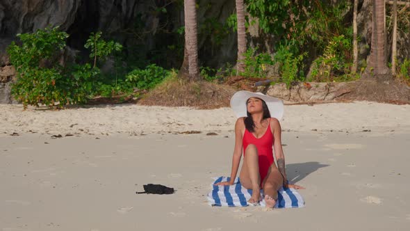 Woman In Swimsuit And Sunhat Sunbathing On Beach alt