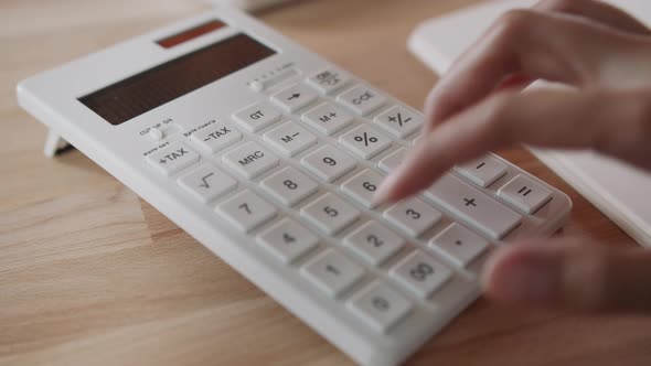 Close up of Businesswoman or female accountant freelancer hand using a calculator calculating alt