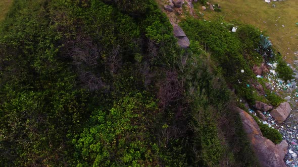 Aerial birdseye dolly right of landscape revealing garbage accumulated on beach alt