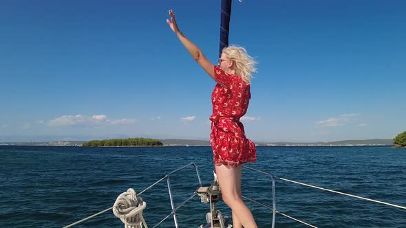 Woman Waving Hello on Bow of a Sailboat alt