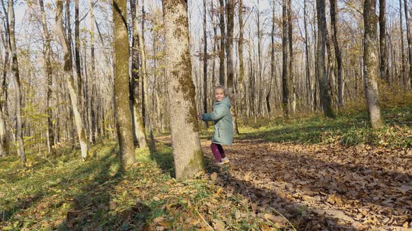 A girl child running with a dog in the autumn forest. The concept of a happy childhood alt