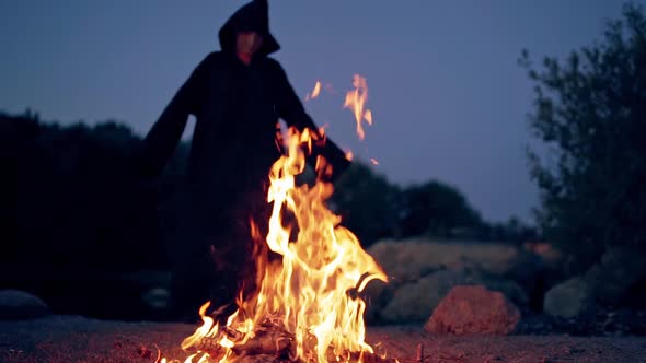 Old evil witch by fire in night forest. Scary Halloween concept alt