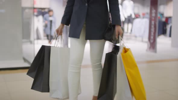 Legs of Woman Walking through Shopping Mall with Lots of Bags alt