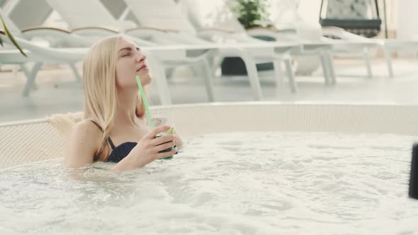 Charming Blonde Woman Resting in Jacuzzi with Soft Drink