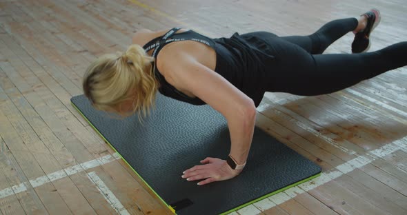 Athletic Woman with Smart Watch Does Pushups As Part of Her Cross Fitness alt