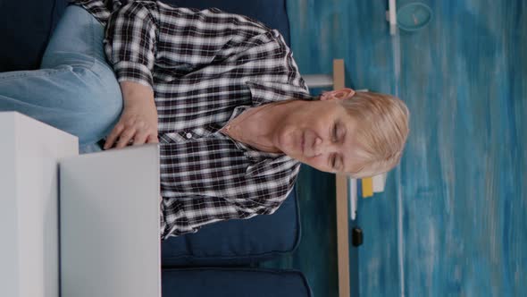 Vertical Video Smiling Senior Couple Looking at Laptop Computer Waving During Videocall alt