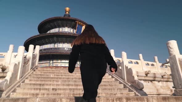 The Girl Tourist Gets Up the Stairs To the Temple of Heaven in Beijing in Winter Sunny Day. Travel