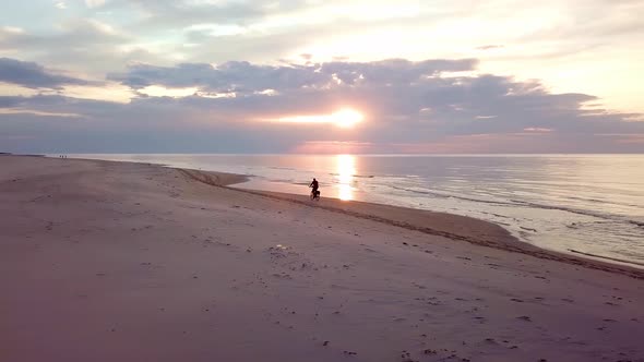 Man Riding Bicycle On Beach at Sunset.