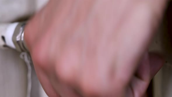 Male hand opening the thermostatic valve of an old white radiator, gas prices concept macro shot in alt