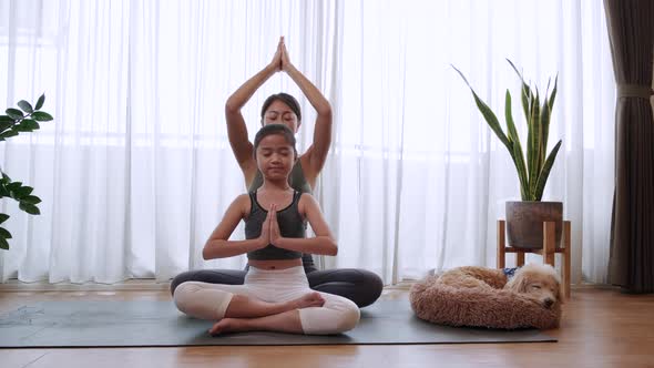 Healthy mom and little girl doing practicing yoga together on yoga mat at home