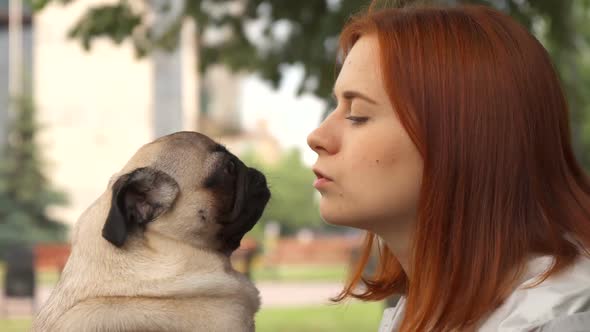 Girl Trying To Kiss Her Pug and Looking at Camera alt