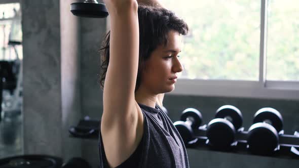 Fit Woman Doing Overhead Triceps Extension Exercise with Dumbbell at the Gym alt