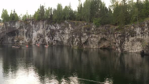 The drone flies at low altitude above the water in a marble canyon