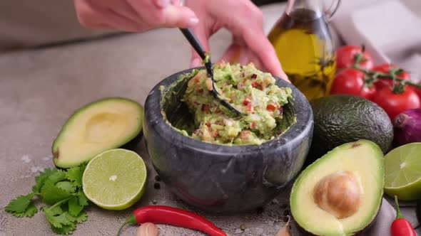 Making Guacamole Sauce  Woman Mixing Chopped Ingredients in Marble Bowl Mortar alt