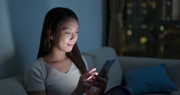 Woman watch on cellphone at home in the evening alt