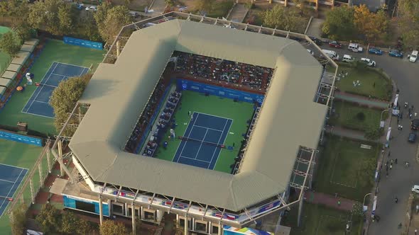 slow orbiting aerial view of a live tennis match playing out in a stadium alt
