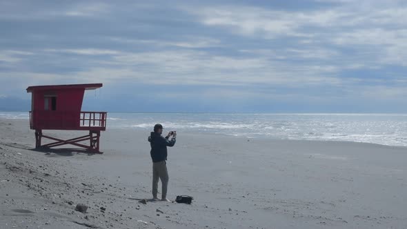 Freelance Photographer on Black Sand Coast Shoots Scenic Seaside Landscape