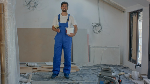 Smiling young worker standing at building house