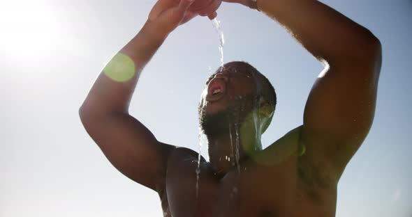 Man pouring water on his head at beach 4k