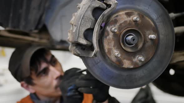 Car Mechanic Tightens the Front Ball Joint of the Car Wheel Hub