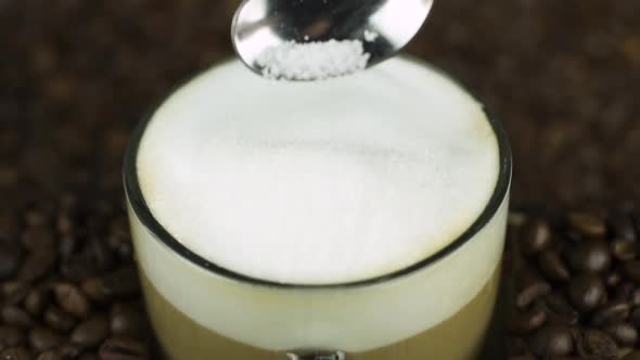 Pour Spoon of Sugar in Coffee Foam, Natural Beans Background. Latte Ingredients alt
