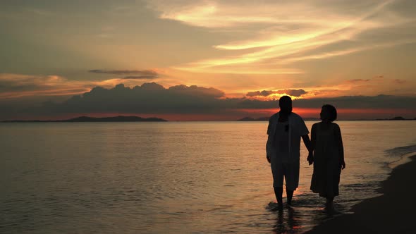 African American man and Asian women Who are lovers walking by the sea in the evening